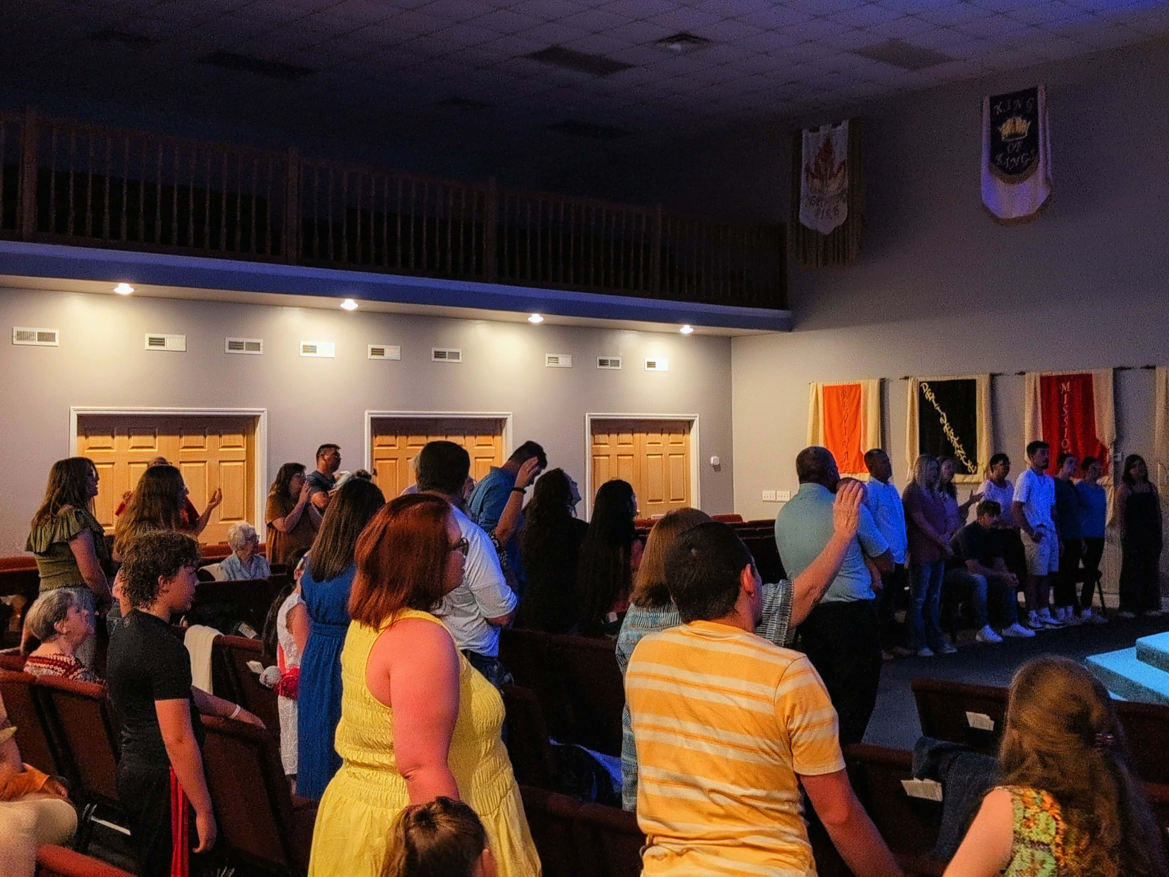 Congregation standing in worship — hands raised